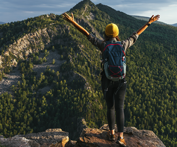 turismo-sostenible-mujer-viajera-de-espaldas-en-pico-de-montana
