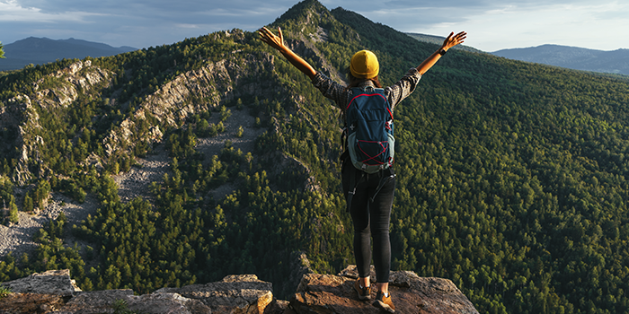turismo-sostenible-mujer-viajera-de-espaldas-en-pico-de-montana