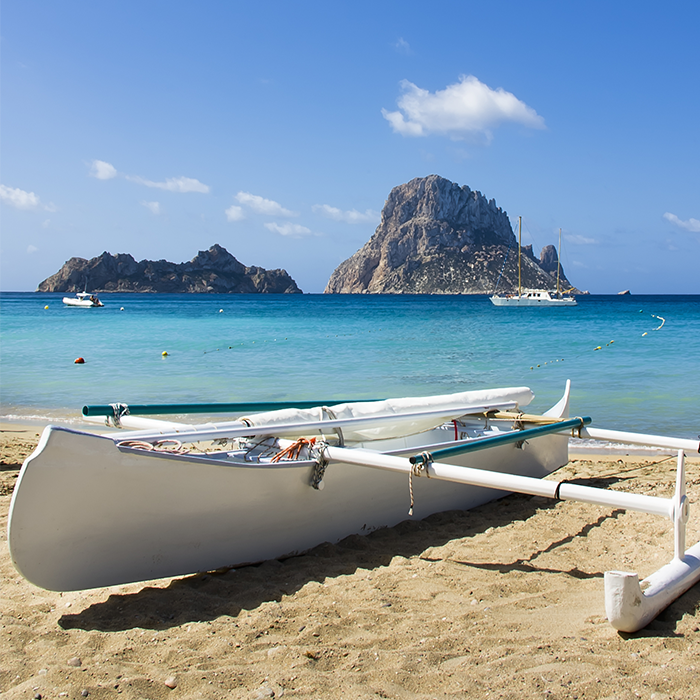 lugares-que-visitar-en-ibiza-mar-azul-y-barco-en-playa