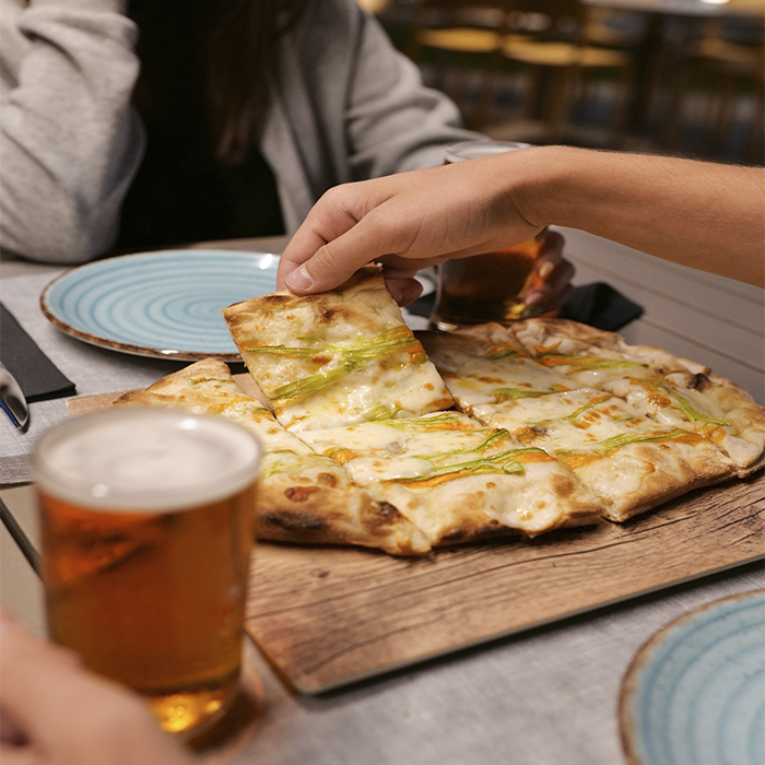 lugares-que-visitar-en-roma-pareja-comiendo-pizza-italiana-en-trattoria-con-cerveza